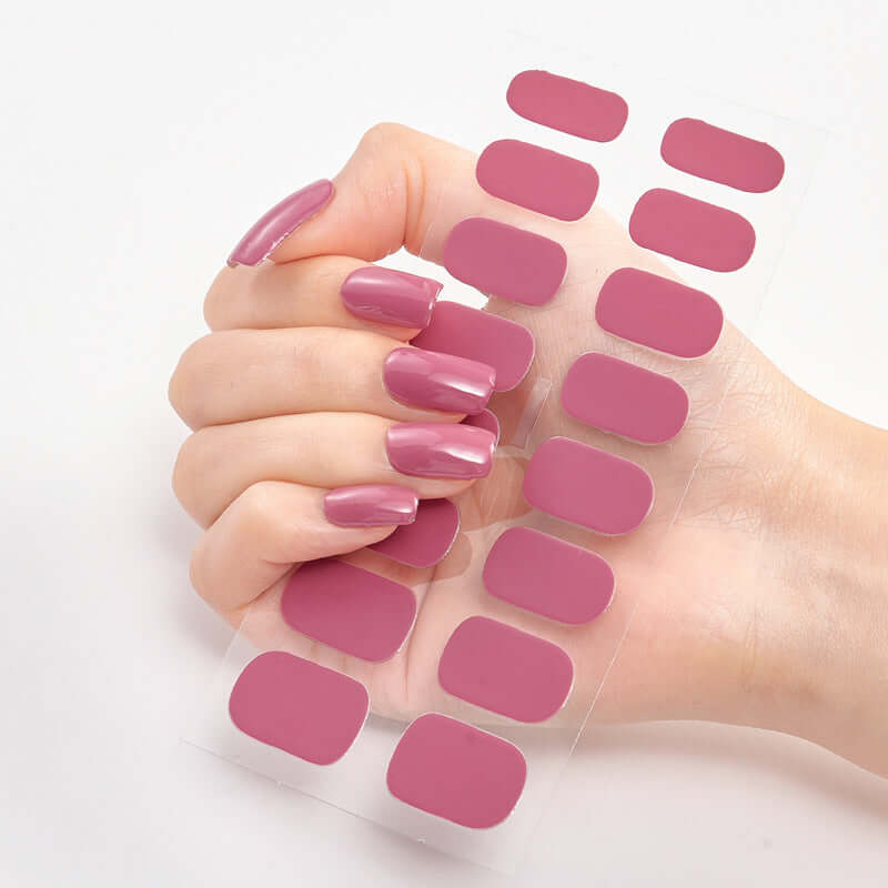 Pink solid color nail stickers displayed on a hand with perfectly manicured nails.