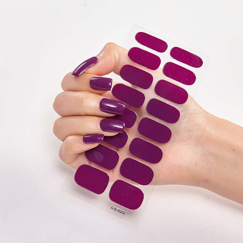 Hand holding Pure Color 16 nail stickers in solid purple shade, showcasing glossy finish and vibrant color options.