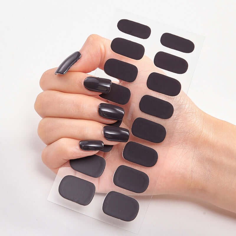Hand holding Pure Color 16 Nail Stickers in solid dark color for stylish nail art.