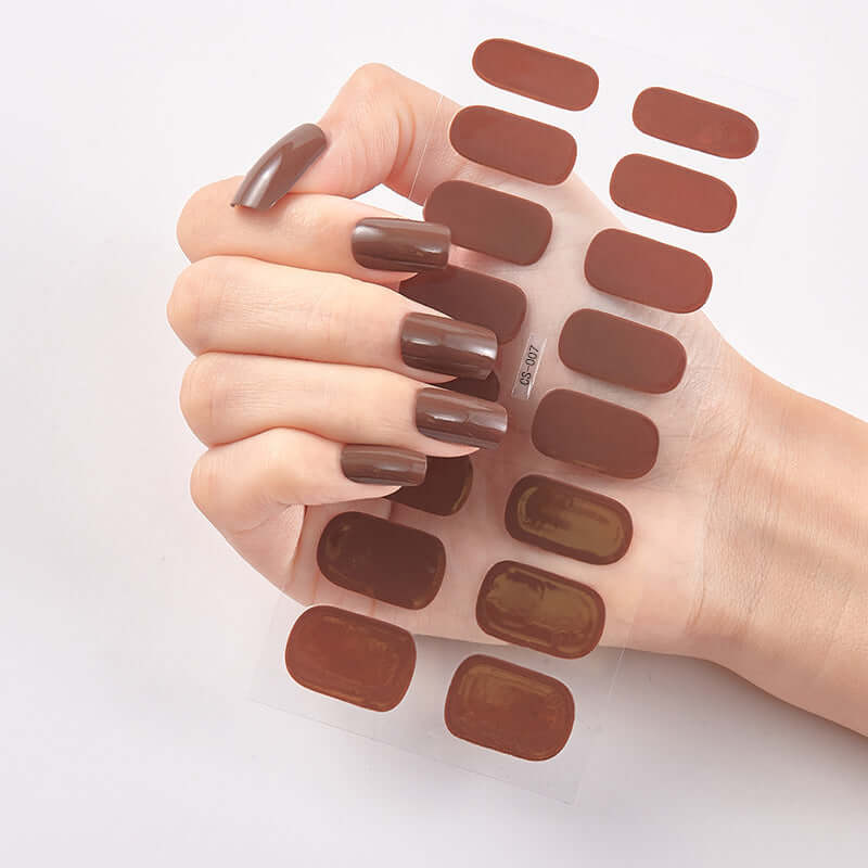 Hand holding Pure Color 16 Nail Stickers featuring solid brown shades for trendy nail art.