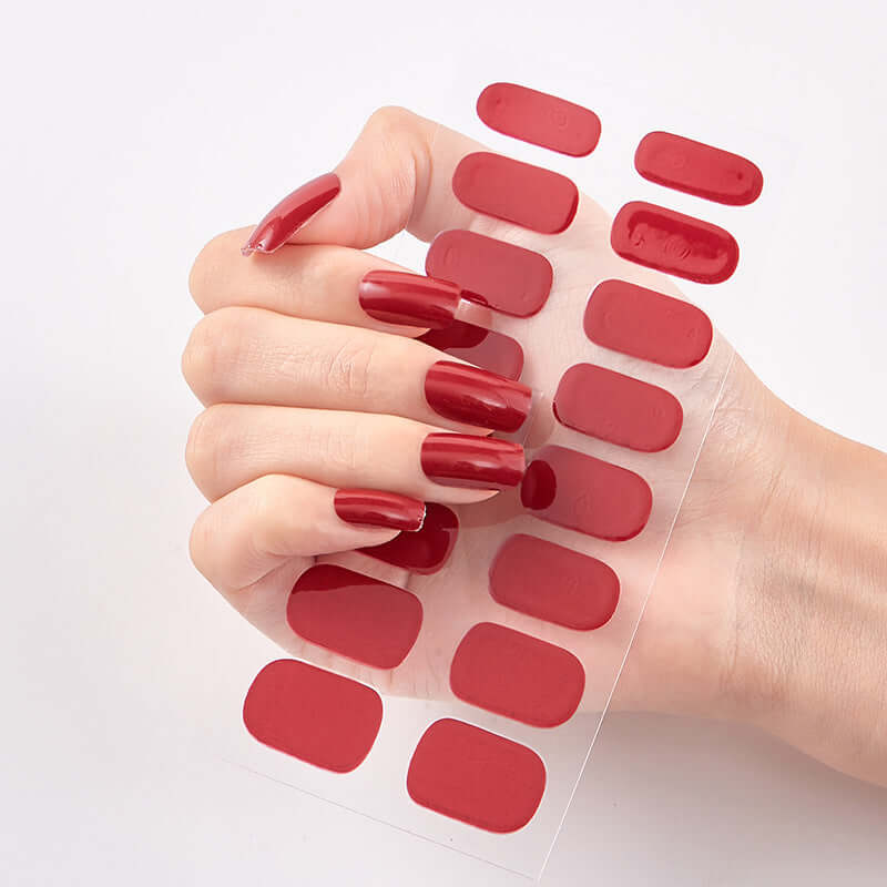 Hand holding red Pure Color 16 nail stickers sheet with glossy finish.