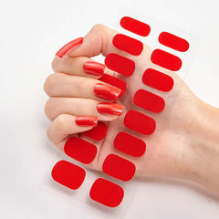 Hand holding sheet of Pure Color 16 red nail stickers with manicured nails.