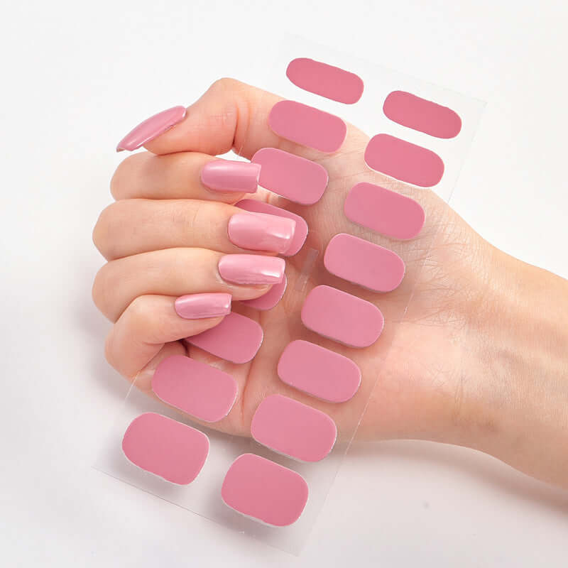 Hand holding a sheet of Pure Color 16 pink nail stickers for stylish nail art and easy application.
