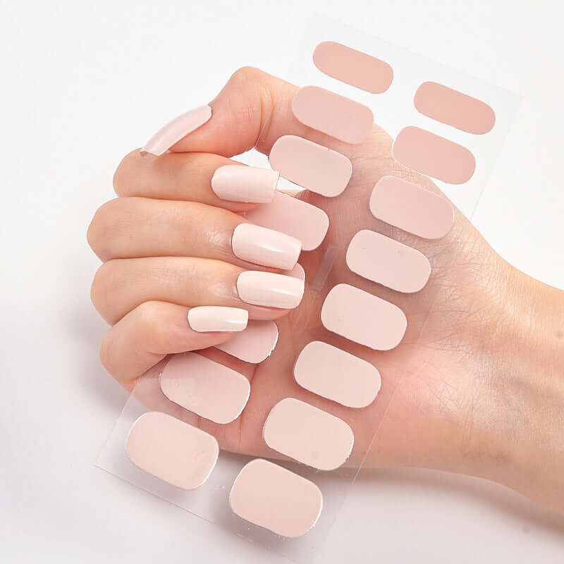 Woman's hand holding a sheet of 16 Pure Color nail stickers with soft pink shades displayed.