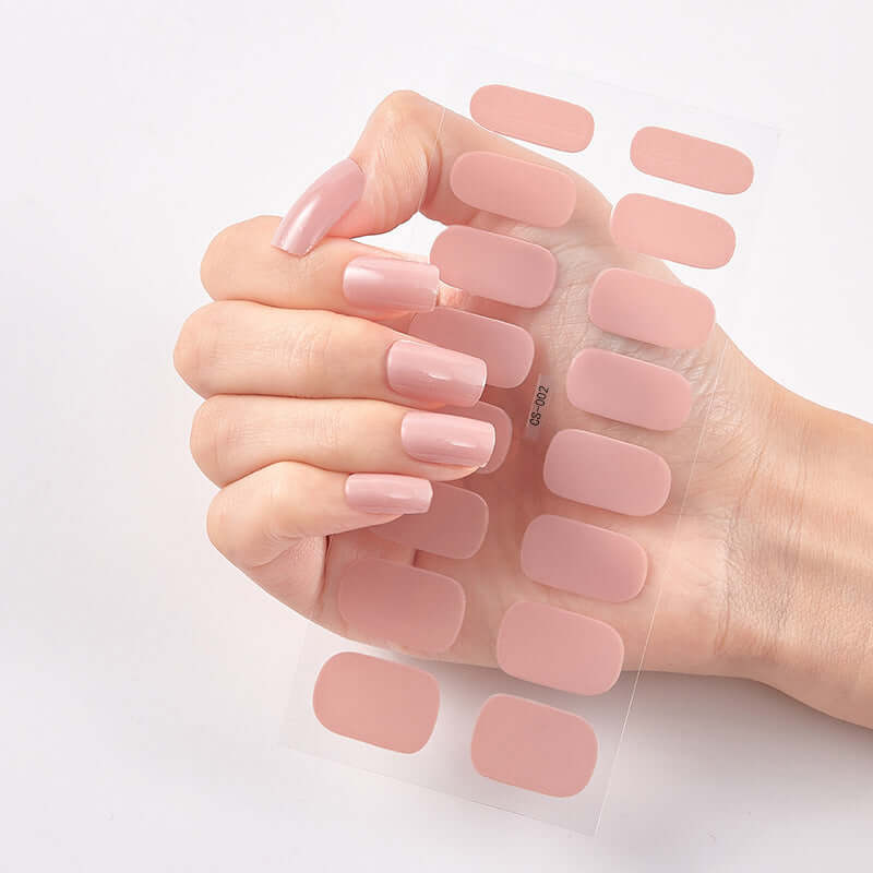 Hand holding Pure Color 16 Nail Stickers in soft pink shades, showcasing eco-friendly design and variety.
