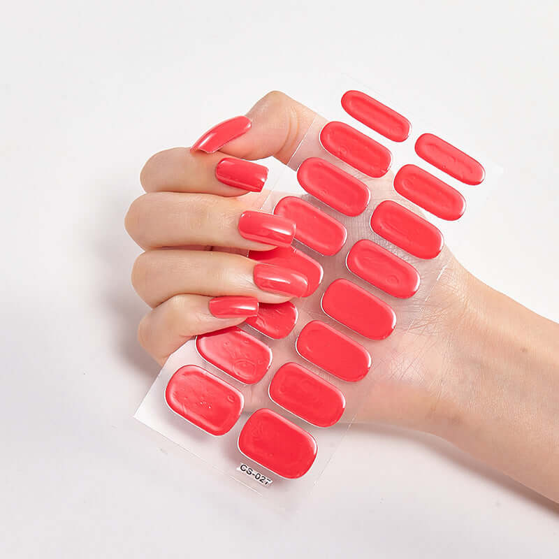 Hand holding Pure Color 16 Nail Stickers in vibrant red shades on a white background.