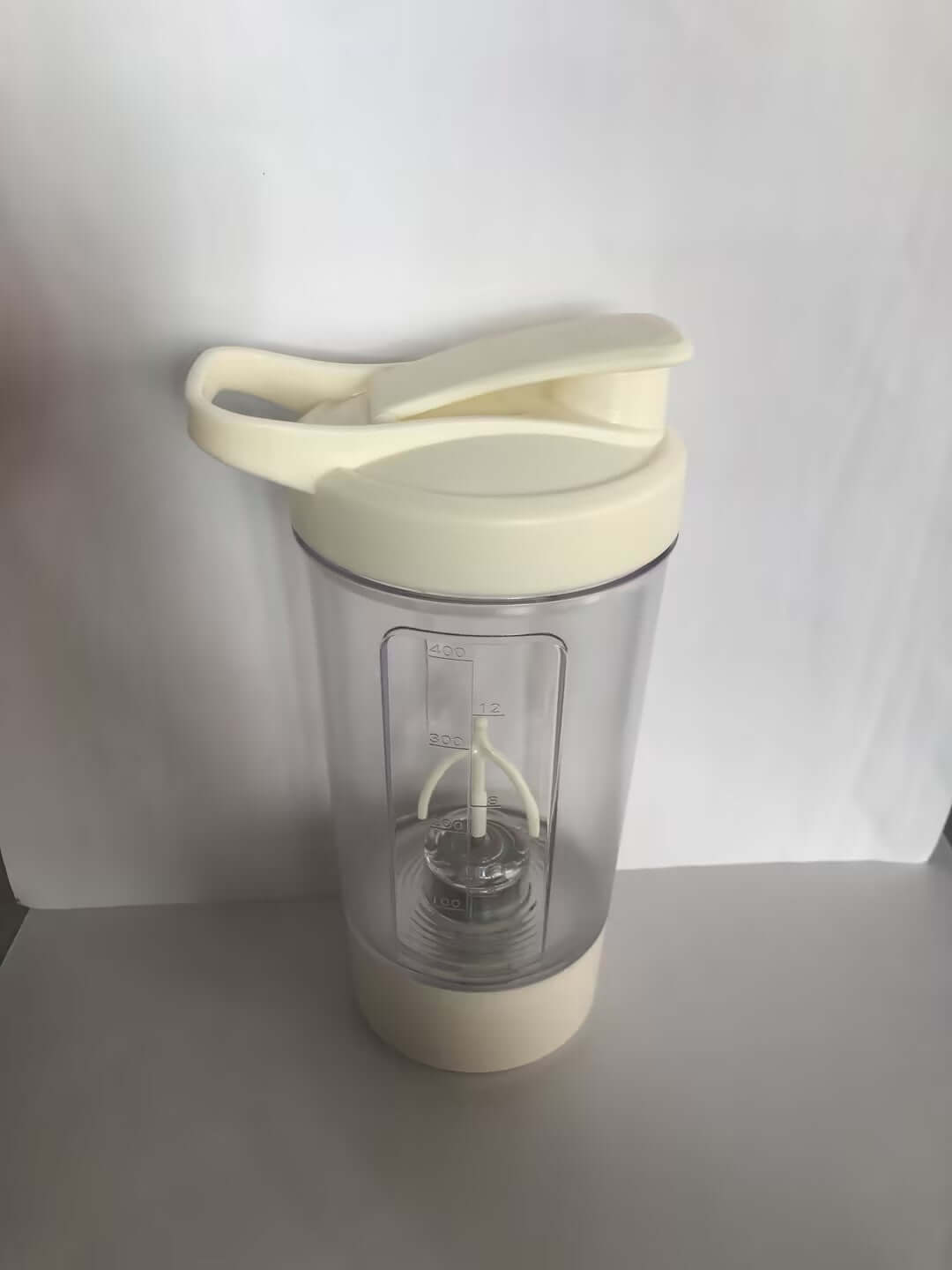 400ML Electric Protein Shaker Bottle with a cream-colored lid and transparent body for smooth mixing of drinks.