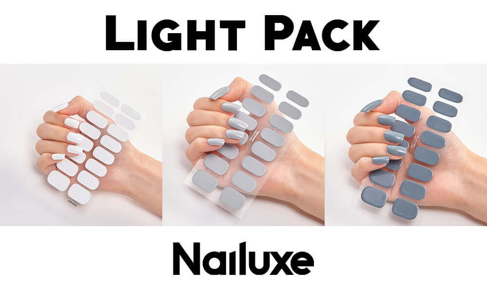 Light pack of Nailuxe nail stickers displayed on a hand, featuring white and gray shades for stylish nails.