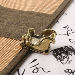 Antique brass Christmas sled ornament on decorative fabric background, perfect for holiday home decor.