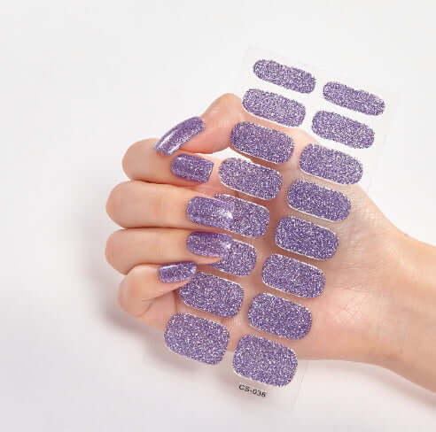 Purple glitter nail stickers on hand showcasing vibrant design for stylish nails.