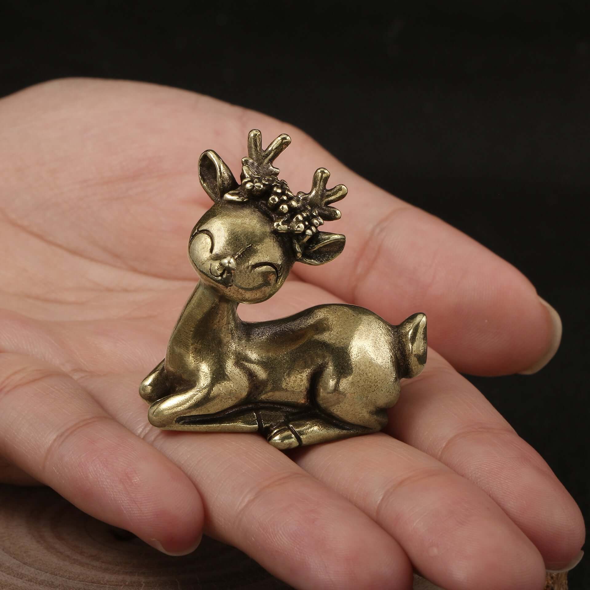 Brass cute male reindeer ornament resting on a hand, perfect for Christmas decor and festive crafting.