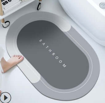 Modern oval bathroom mat in gray color with the word 'BATHROOM' printed, designed for absorbency and quick drying.
