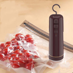 Portable electric vacuum sealer with attachment on vacuum storage bag filled with cherry tomatoes.