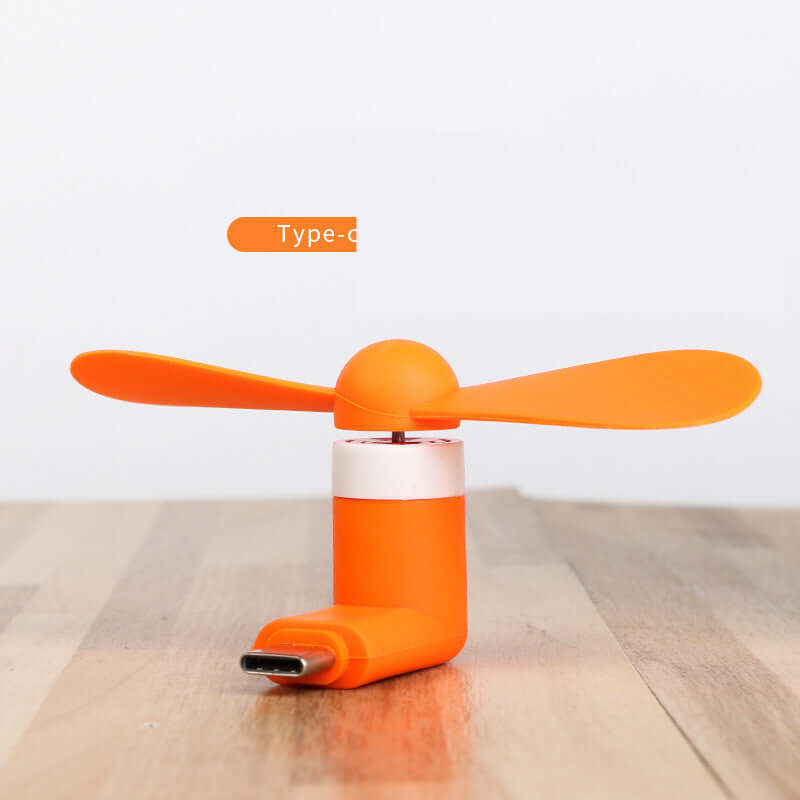 Compact orange mobile mini fan with USB connector, compatible with iPhone and Android for cool breezes on-the-go.