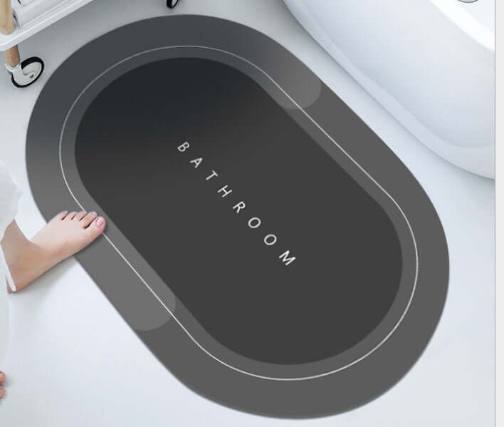 Modern oval bathroom mat in dark gray with 'BATHROOM' text, providing absorbent and quick-drying features.