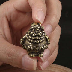 Hand holding a brass Santa figurine with detailed clothing and a joyful expression, perfect for Christmas decor.