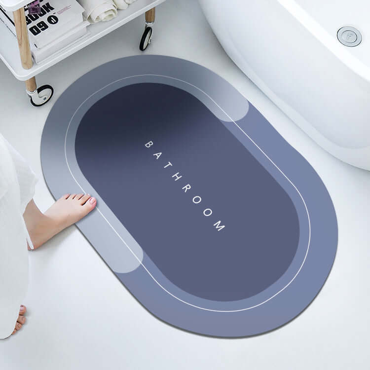 Modern oval bathroom floor mat in dark blue with 'BATHROOM' text, absorbent and quick-drying for home use.