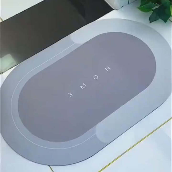Modern oval floor mat with 'HOME' text, quick-drying, in elegant gray, suitable for home entryways and bathrooms.