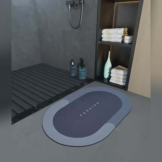 Fashionable oval quick-drying bathroom mat in dark gray, placed next to shower, complementing modern decor.