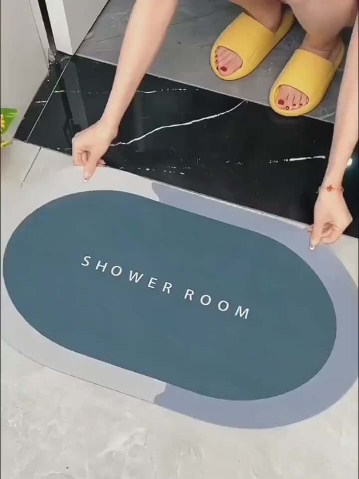 Person placing a modern oval bathroom mat labeled 'SHOWER ROOM' on a floor, showcasing its absorbent design.