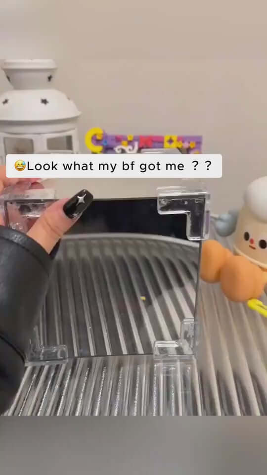 Hand holding a small, clear mirror with a decorative background, showing a romantic gift from a boyfriend.