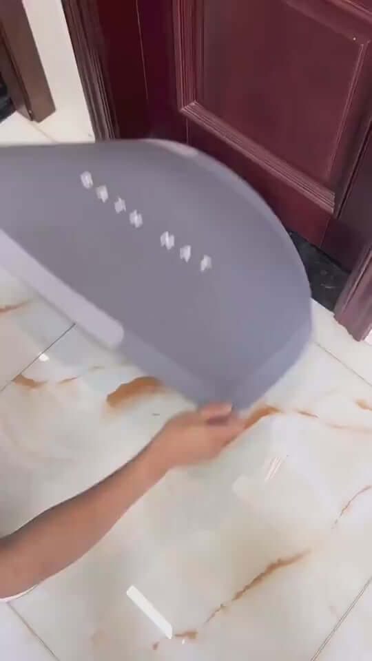 Person holding a modern gray oval bathroom floor mat, designed for quick-drying and absorbency.