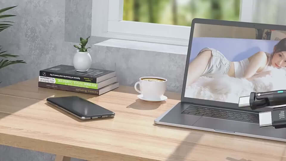 Modern workspace featuring a laptop, mobile phone, coffee cup, and books on a desk with natural light.