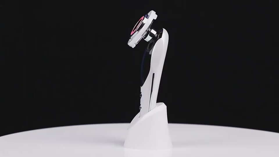 7-in-1 facial massager with LED light and vibration features on a white stand for skin care.