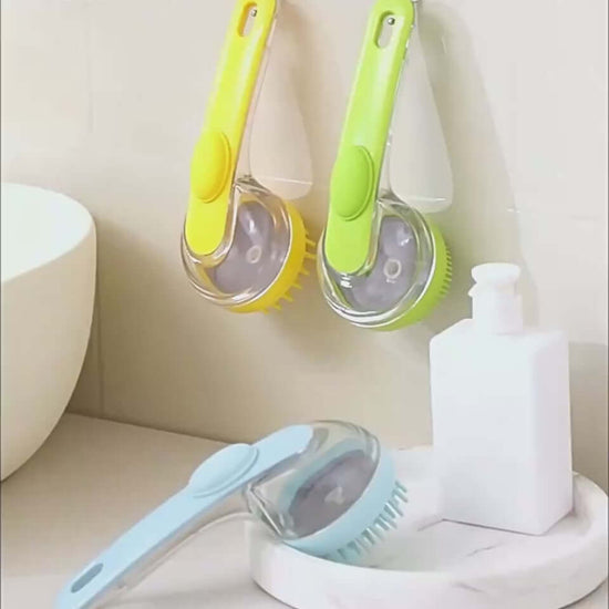 Long handle pet bath brushes in yellow and green, displayed beside a soap dispenser for pet grooming.