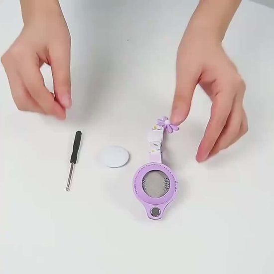 Hands assembling a reflective collar case for AirTag in purple with tools on a table, showcasing its protective features.