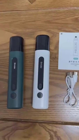 Electric dog nail grinders in green and white with user manual and charging cable on wooden surface.