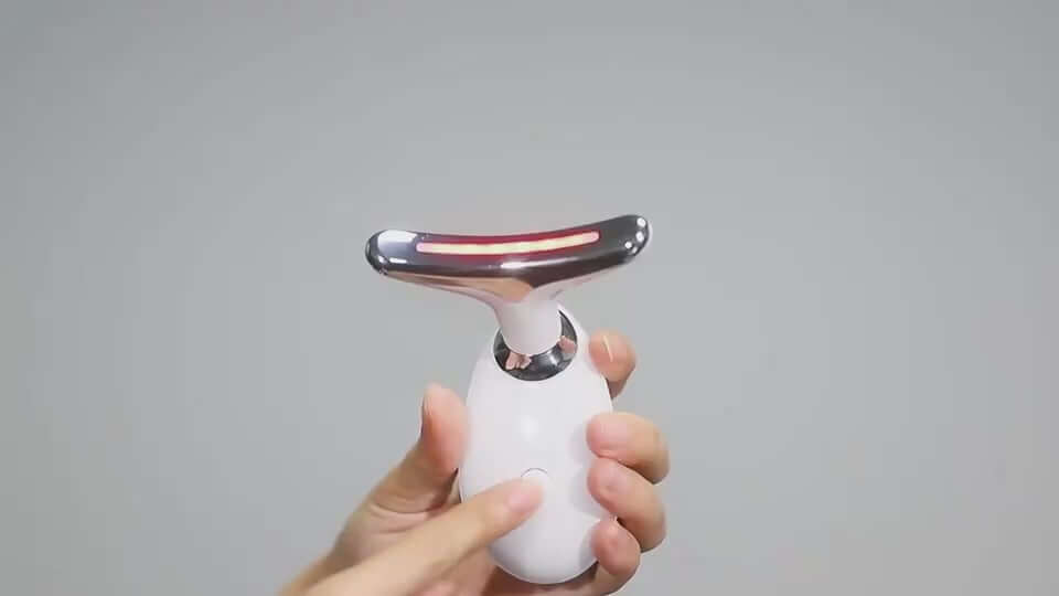 Hand holding EMS Thermal Neck Lifting Massager with red light for skin tightening and wrinkle removal.