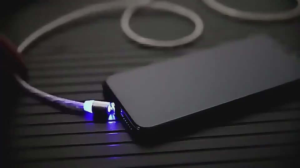 Magnetic streaming data cable connected to smartphone, featuring blue LED light and a sleek design for easy charging.