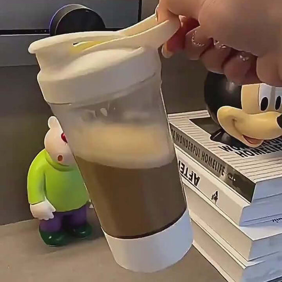 Hand holding a 400ml electric shaker bottle filled with coffee, ideal for gym use and convenient mixing.