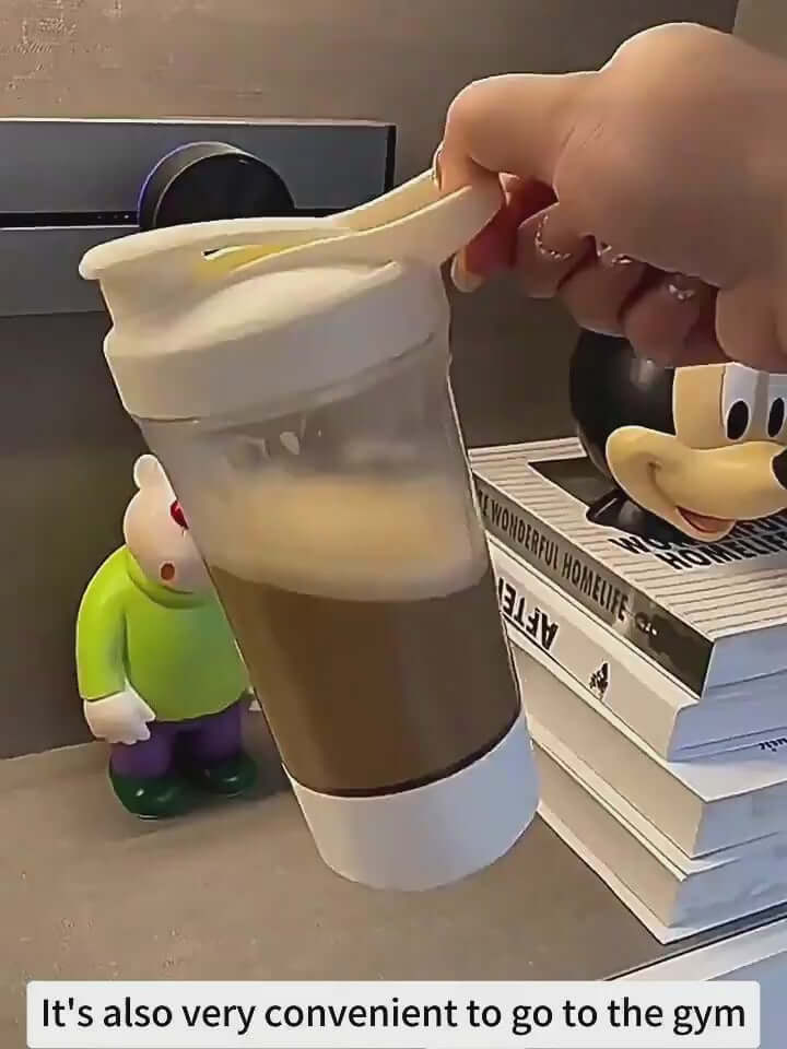 Hand holding a 400ml electric shaker bottle filled with coffee, ideal for gym use and convenient mixing.